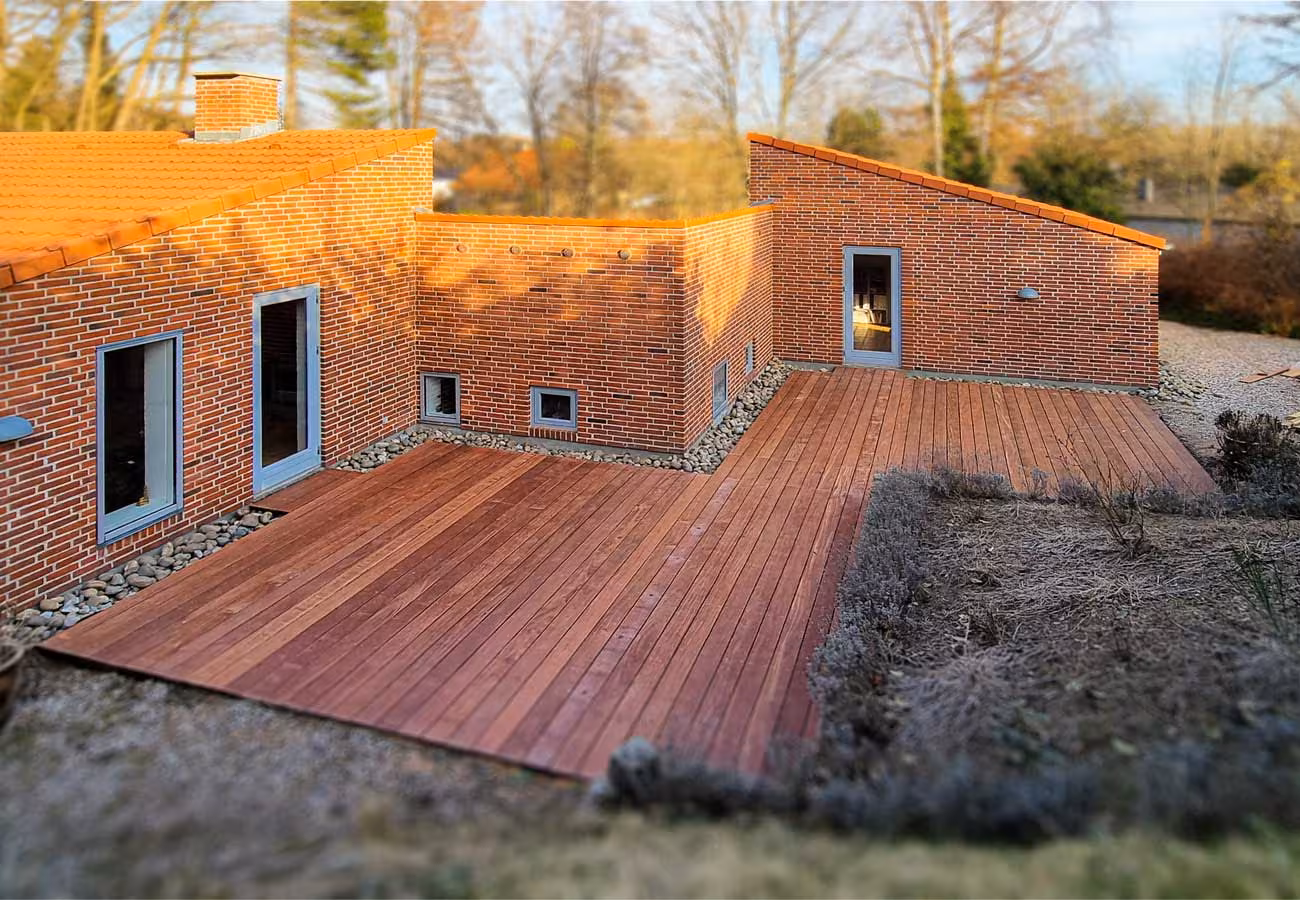 Terrassedæk i vinkel langs rødt murstenshus i Hillerød