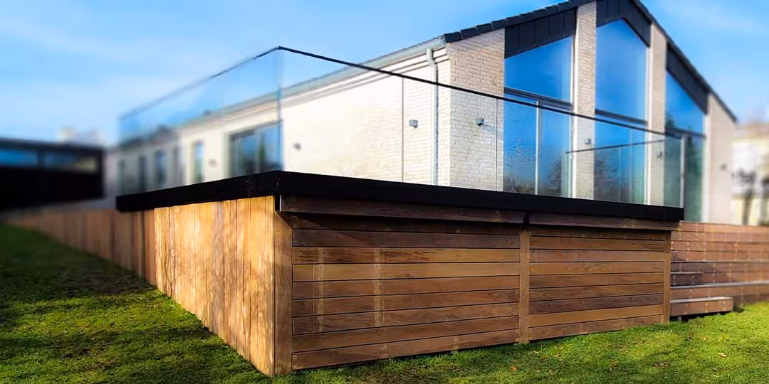 Hævet terrasse med glasværn og træbeklædt forkant på moderne hus