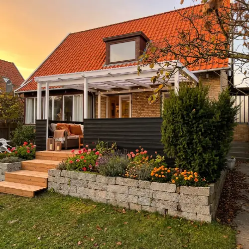 En smuk hævet træterrasse med hvid overdækning og integreret trappe bygget i Lyngby